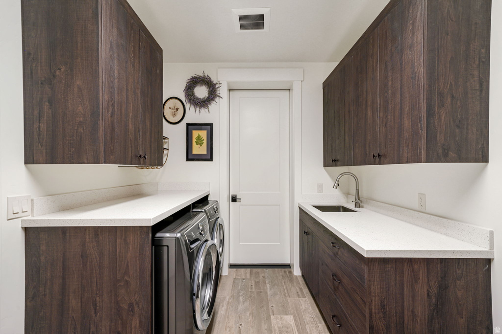 Laundry room with ample dark wood-finish cabinetry, light-toned countertops, a utility sink with a gooseneck faucet, and wood-finish flooring