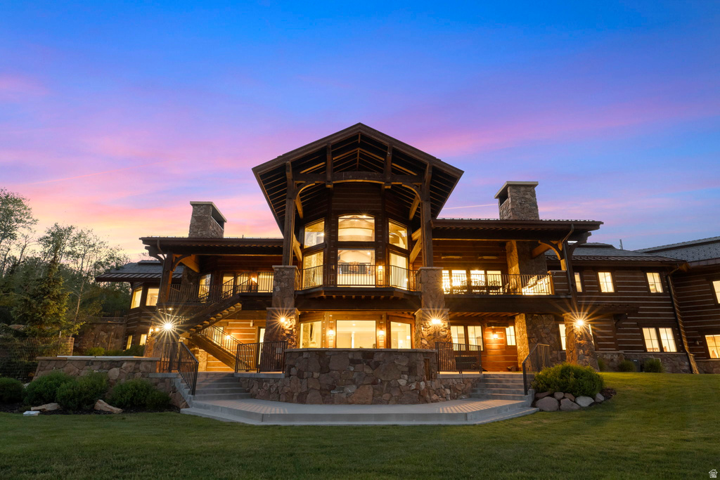 Custom log home featuring extensive stonework, multiple balconies, a grand exterior staircase, and large windows