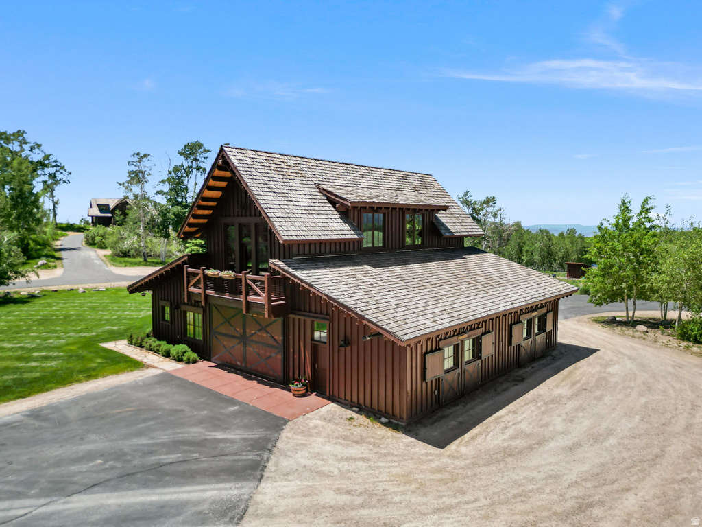 Rustic-style structure featuring a wood-shingle roof, wood siding, and multiple windows with exterior shutters
