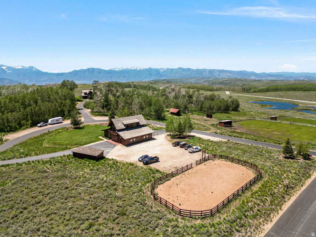 Expansive property featuring a rustic-style home with a dormer roof, a fenced arena, and multiple outbuildings