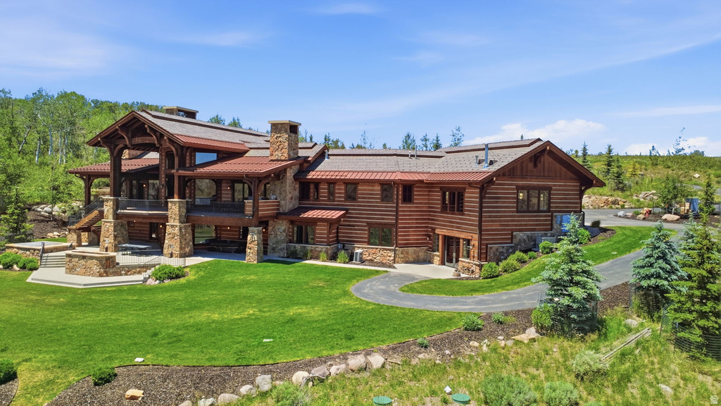 Expansive log home with stone accents, a multi-level deck, and a stone outdoor fireplace