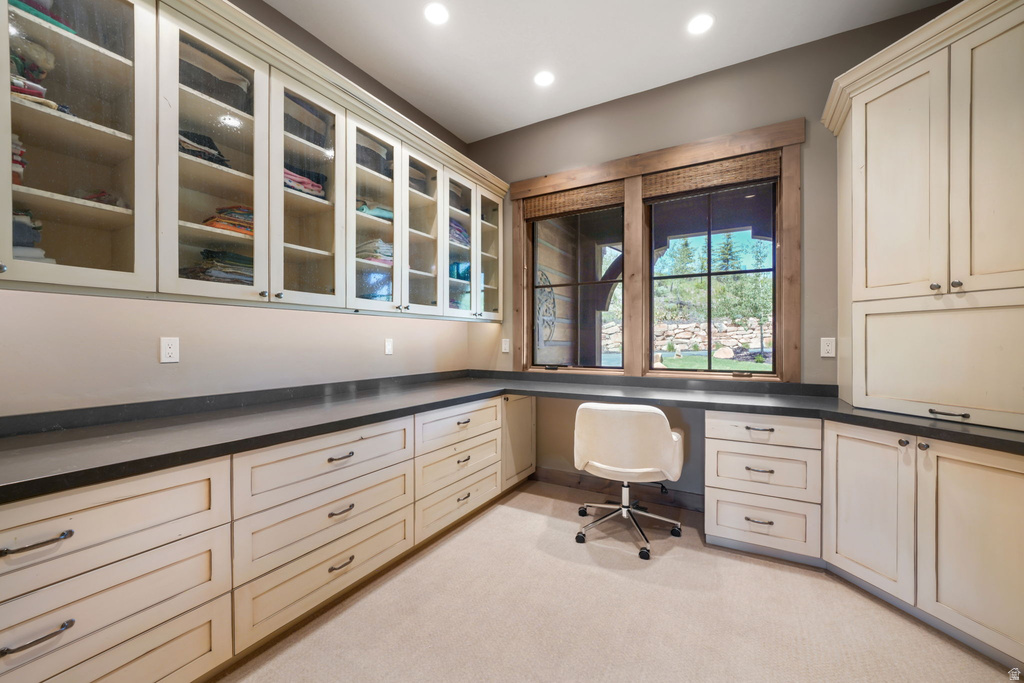 Built-in cabinetry with glass-front uppers and solid lower storage, dark countertops, recessed lighting, and a window with wood trim