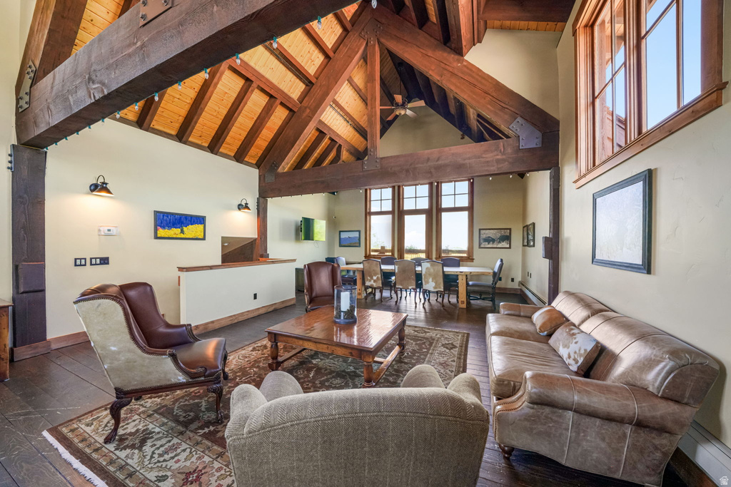 Great room featuring a vaulted ceiling with exposed wood beams, wood-finish flooring, and multiple large windows