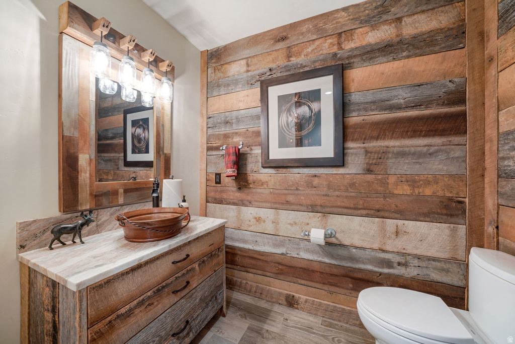Reclaimed wood accent wall and vanity featuring a rectangular vessel sink, stone countertop, and wood-framed mirror with jar lighting fixtures