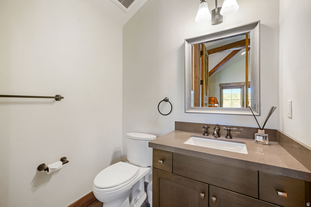 Vanity featuring a rectangular undermount sink, a solid surface countertop, and dark wood-finish cabinetry