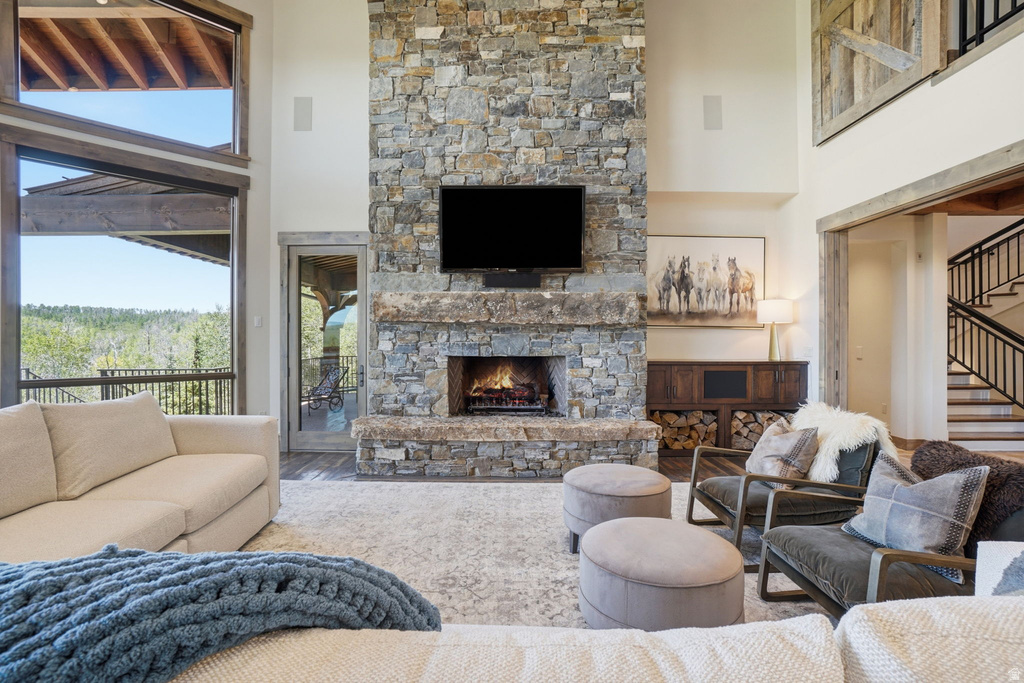 Two-story stone fireplace with hearth, wood-finish flooring, and high ceilings