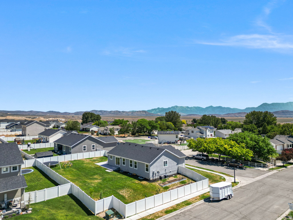 Expansive backyard featuring a manicured lawn, white vinyl fencing, and distant mountain scenery
