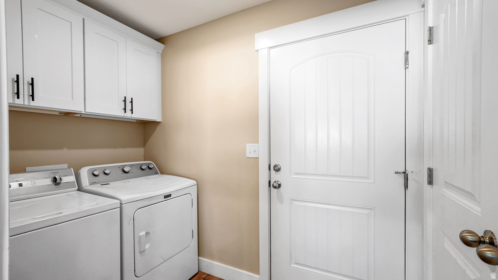 Laundry area featuring white cabinetry with black hardware, complementing the light beige wall tones