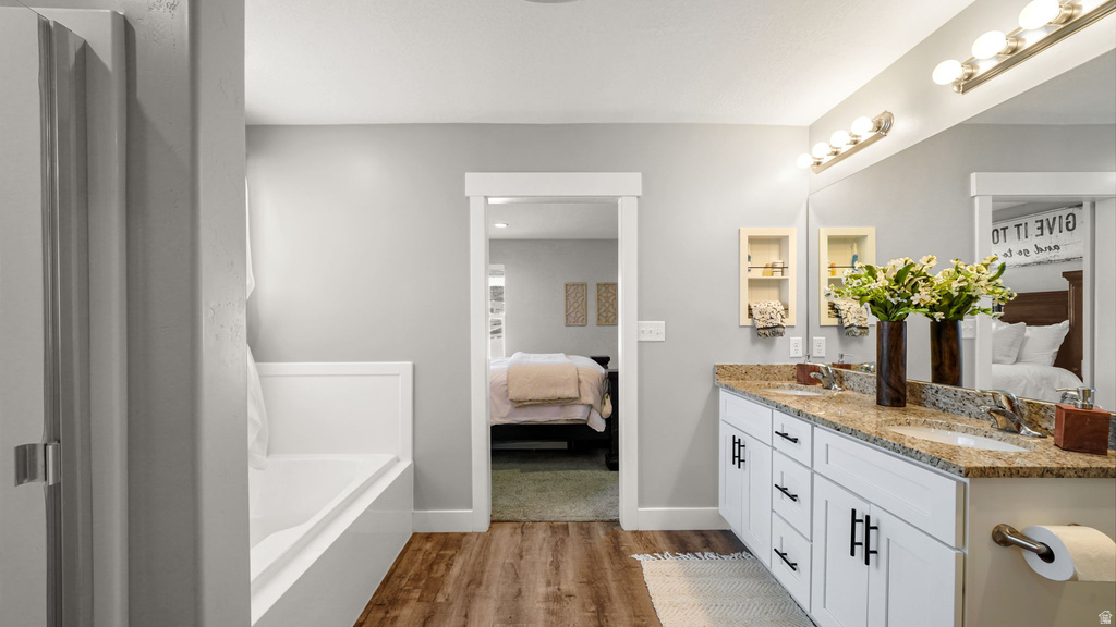 Bathroom featuring a dual vanity with a speckled countertop, undermount sinks, and white cabinetry with black hardware