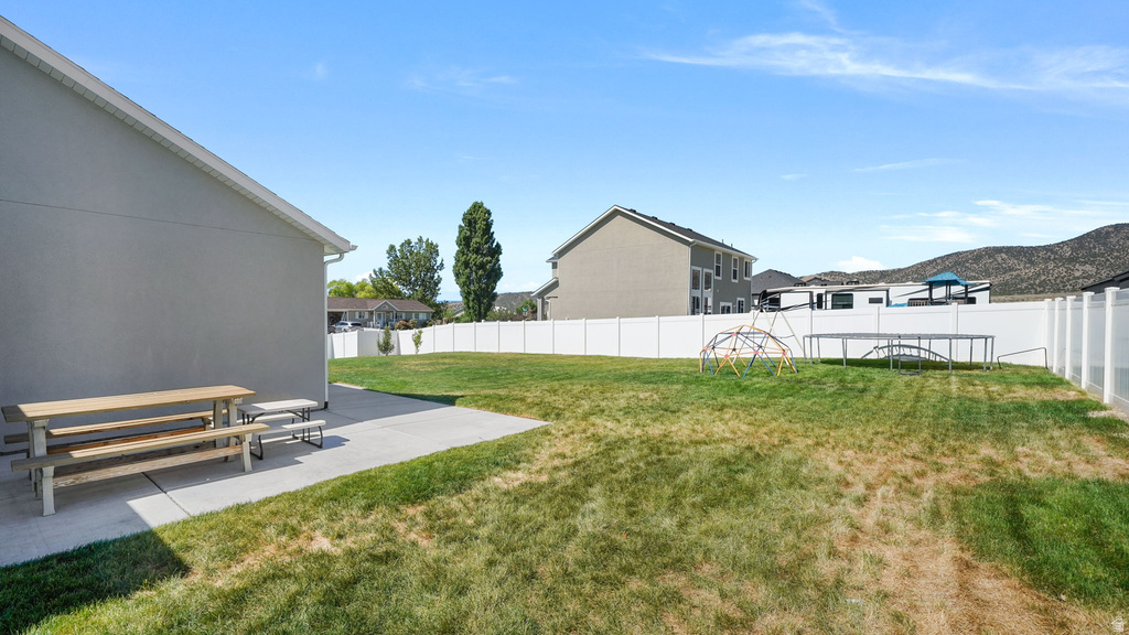 Expansive backyard featuring a concrete patio, a large grass area, and a privacy fence