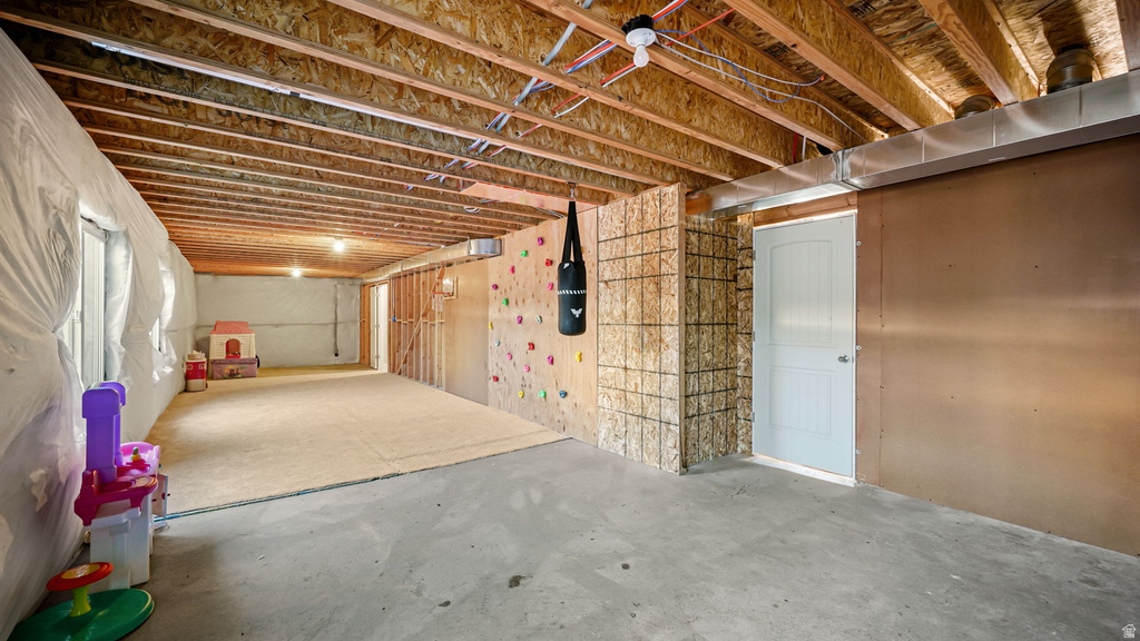 Unfinished basement space featuring exposed wood joists, concrete flooring, and a partially framed wall with a light-colored door