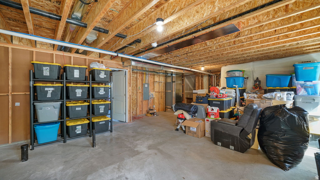 Unfinished basement space featuring exposed wood joists and subflooring, concrete flooring, and visible utility lines