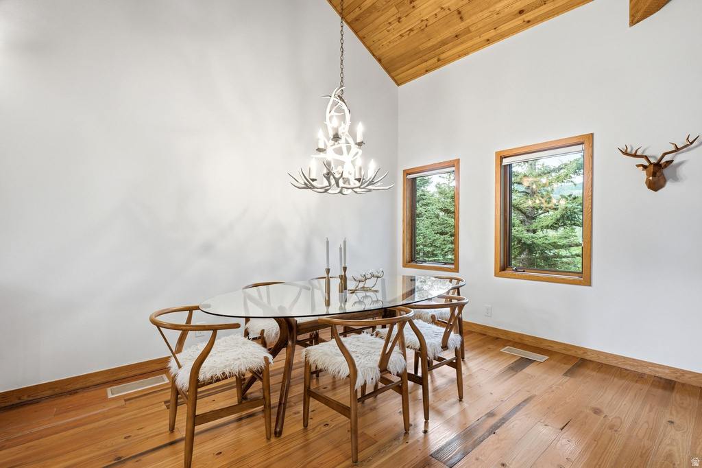 Dining area featuring vaulted wood-paneled ceilings, natural wood-finish flooring, and a decorative antler-style chandelier