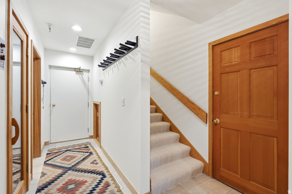 Entryway featuring a wood-panel door, carpeted staircase, and recessed lighting