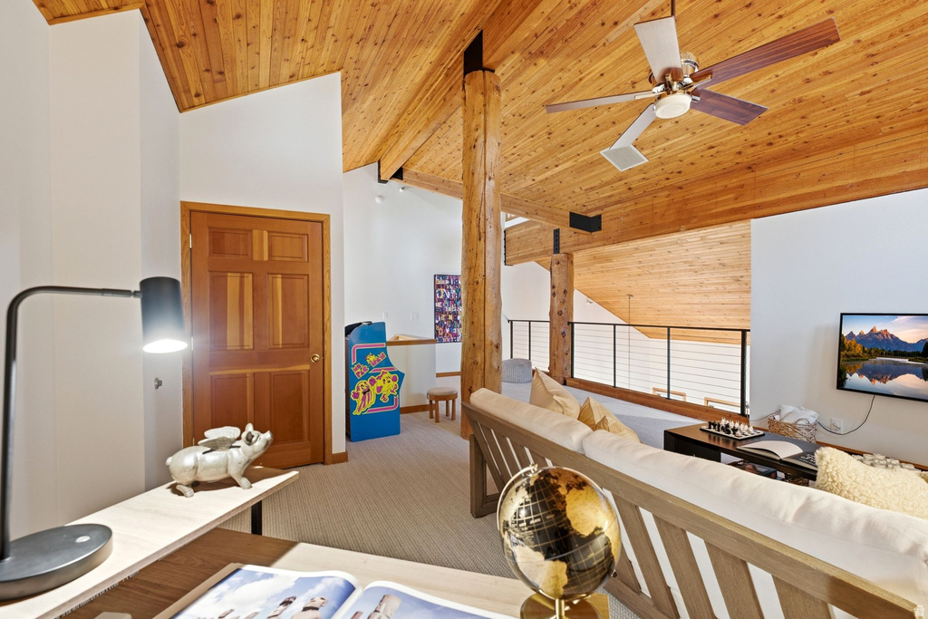 Vaulted wood plank ceiling with exposed wood beams and a ceiling fan