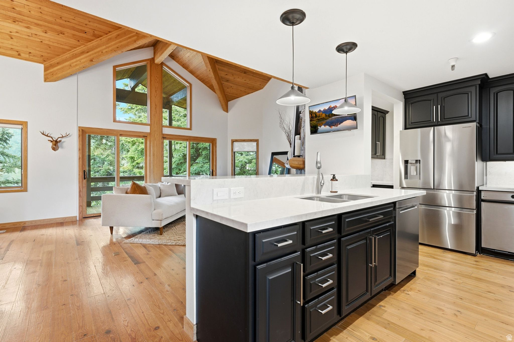 Open-concept living space featuring a kitchen island with a double basin sink and pendant lighting