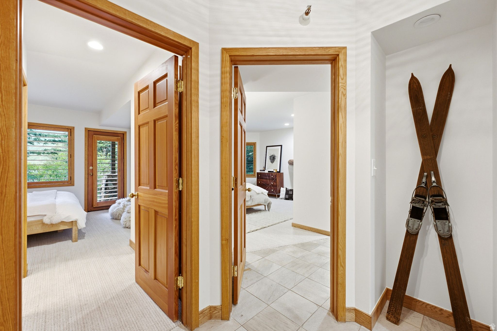 Interior hallway with light tile flooring, white walls, and wood trim