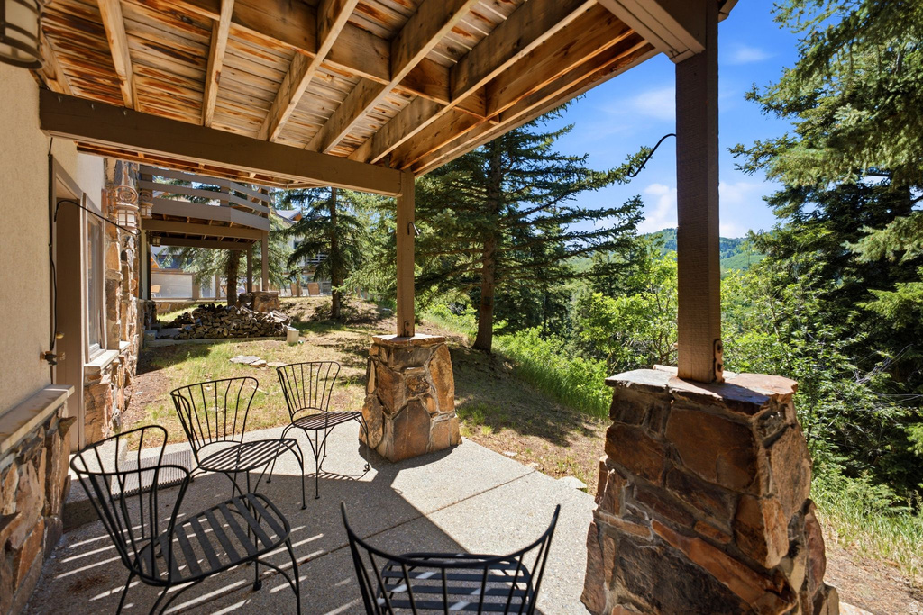 Covered patio with a concrete slab, supported by timber beams and stacked stone columns