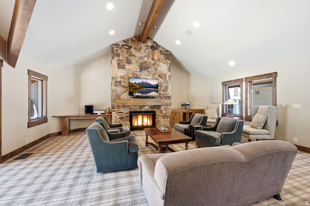 Spacious vaulted living area featuring a prominent stone-clad fireplace and hearth