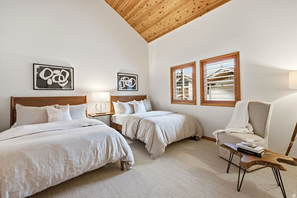 Vaulted wood-paneled ceiling accentuates this bright room featuring light-colored carpeting, two wood-framed windows with louvered blinds, and white walls
