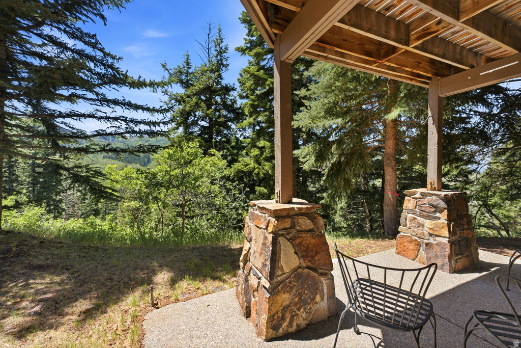 Covered patio featuring stone-clad pillars, a wood-slat ceiling, and a concrete surface
