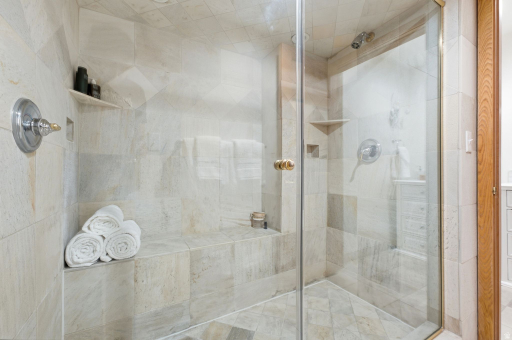 Tiled shower enclosure featuring a glass door, built-in bench, and integrated shelving