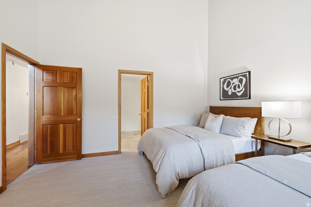 Room featuring high ceilings, light-toned carpeting, and warm wood-finish interior doors