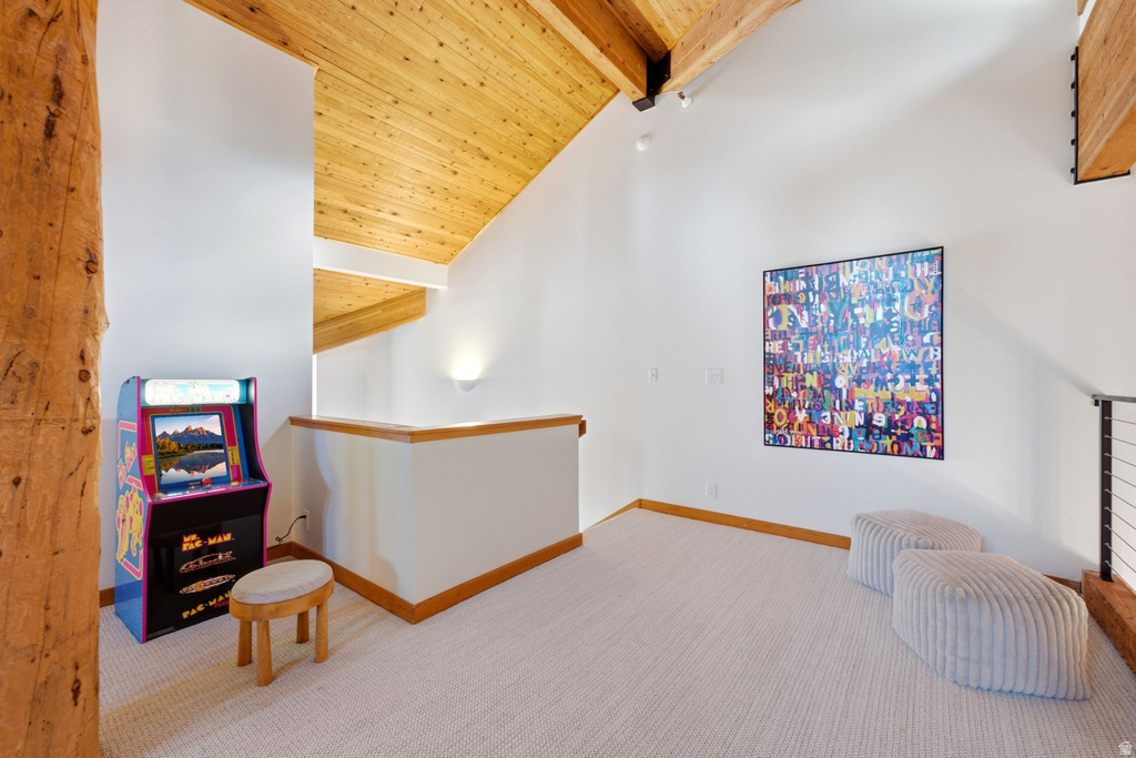 Vaulted wood-finish ceilings with exposed beams, white walls, and light-colored carpeting define this open area