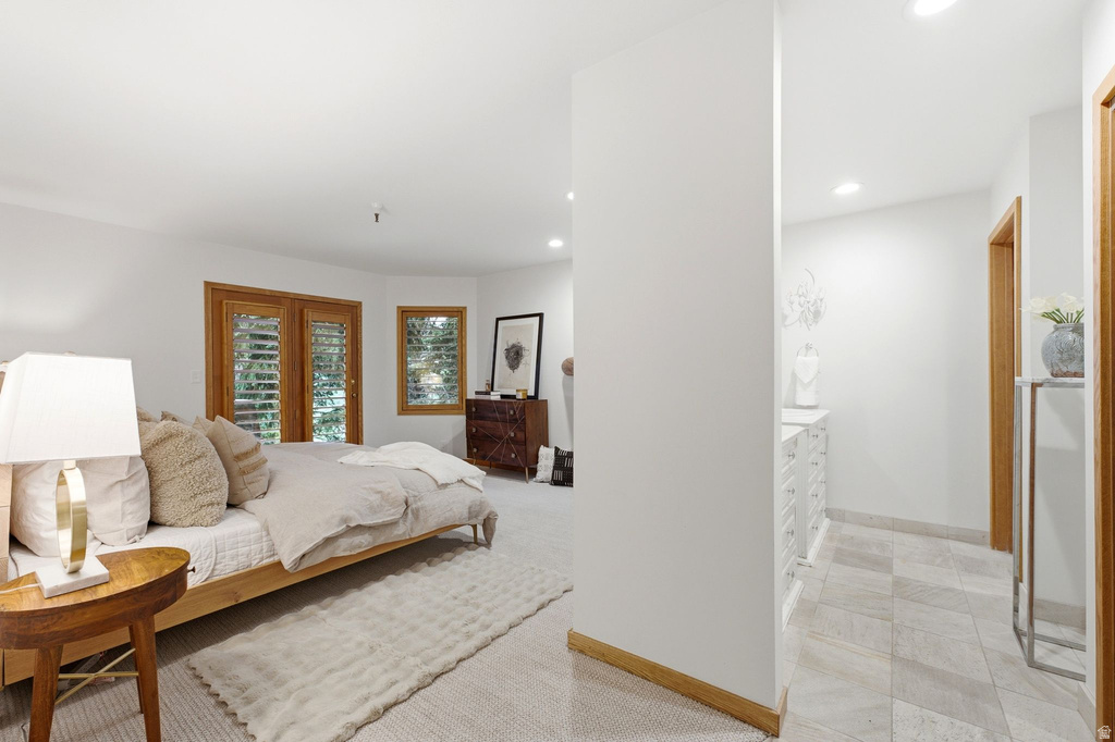 Spacious room featuring wood-finish French doors and an additional window with plantation shutters