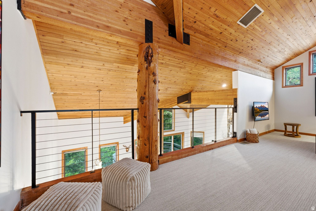 Loft space featuring a vaulted wood-paneled ceiling, exposed wood beam, cable railing, and light-colored carpet