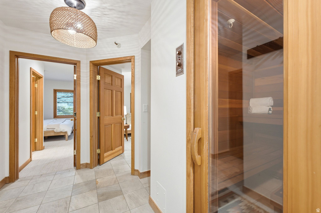 Hallway featuring light-toned tile flooring and a woven ceiling fixture