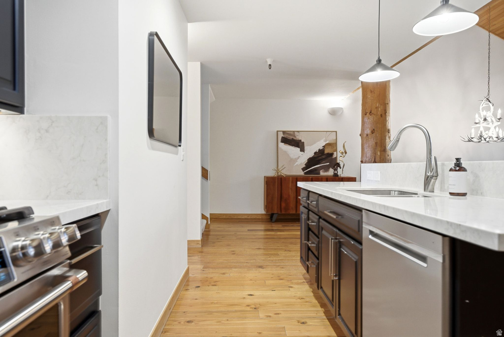 Modern kitchen featuring stone countertops, stainless steel appliances, dark wood cabinetry, and wood-finish flooring