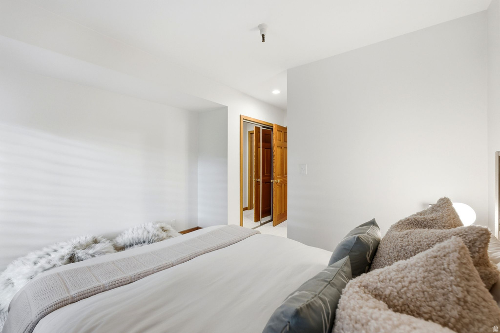 Bedroom featuring light-toned walls, hardwood doors, and recessed lighting