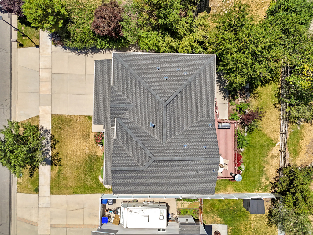Gable roofline home featuring a dark shingle roof, concrete driveway, and a wood-finish deck
