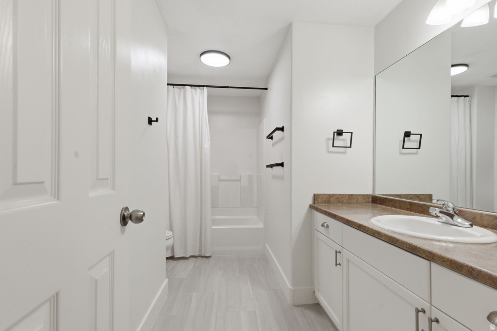 Bathroom featuring a single vanity with an integrated sink, a large wall-mounted mirror, and white cabinetry