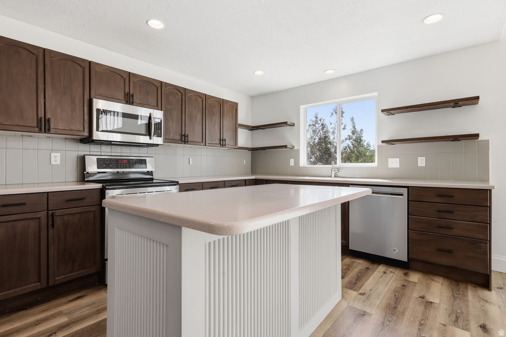 Modern kitchen featuring dark wood cabinetry, light countertops, and wood-finish flooring