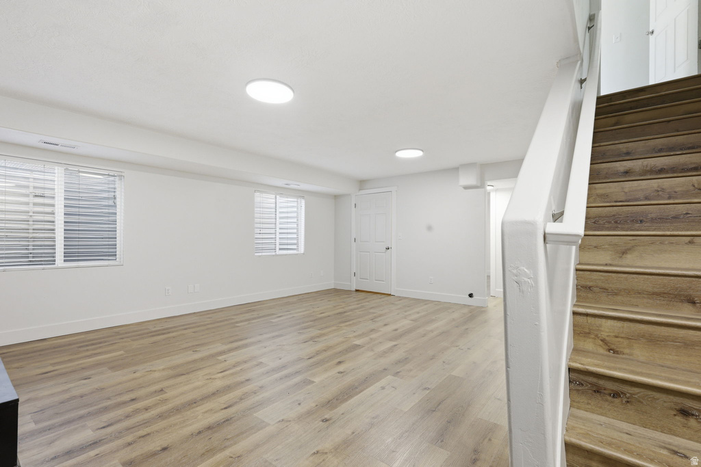 Spacious room featuring wood-finish flooring, white walls, and recessed lighting
