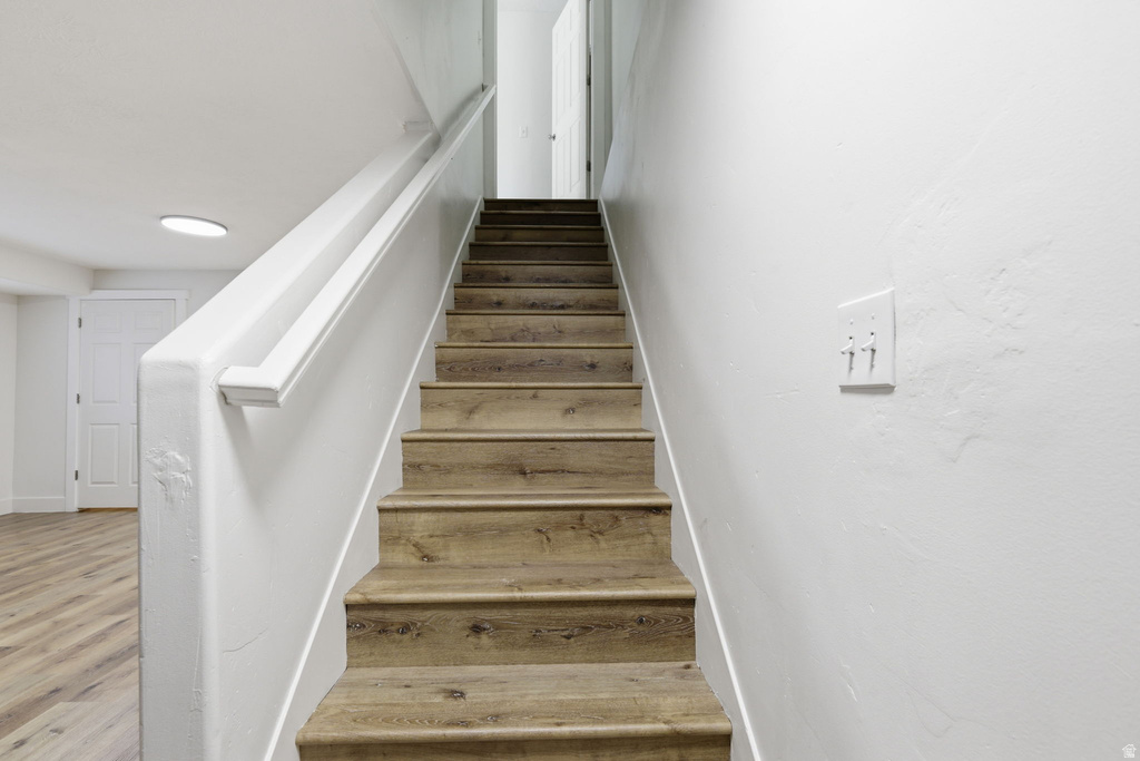 Staircase featuring wood-finish treads and risers with a white handrail