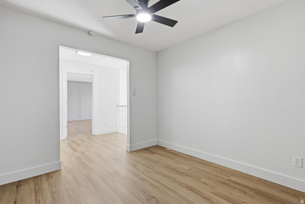 Spacious interior with wood-finish flooring, a contemporary ceiling fan, and white baseboards