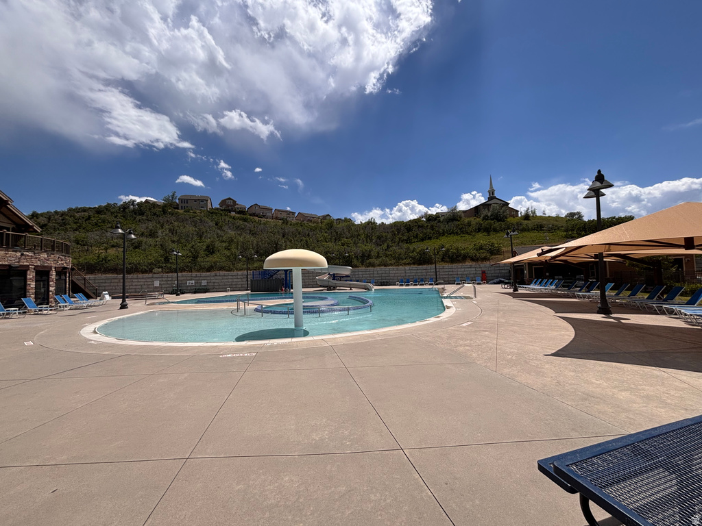 Resort-style pool area featuring a large swimming pool, built-in water features, and ample concrete decking