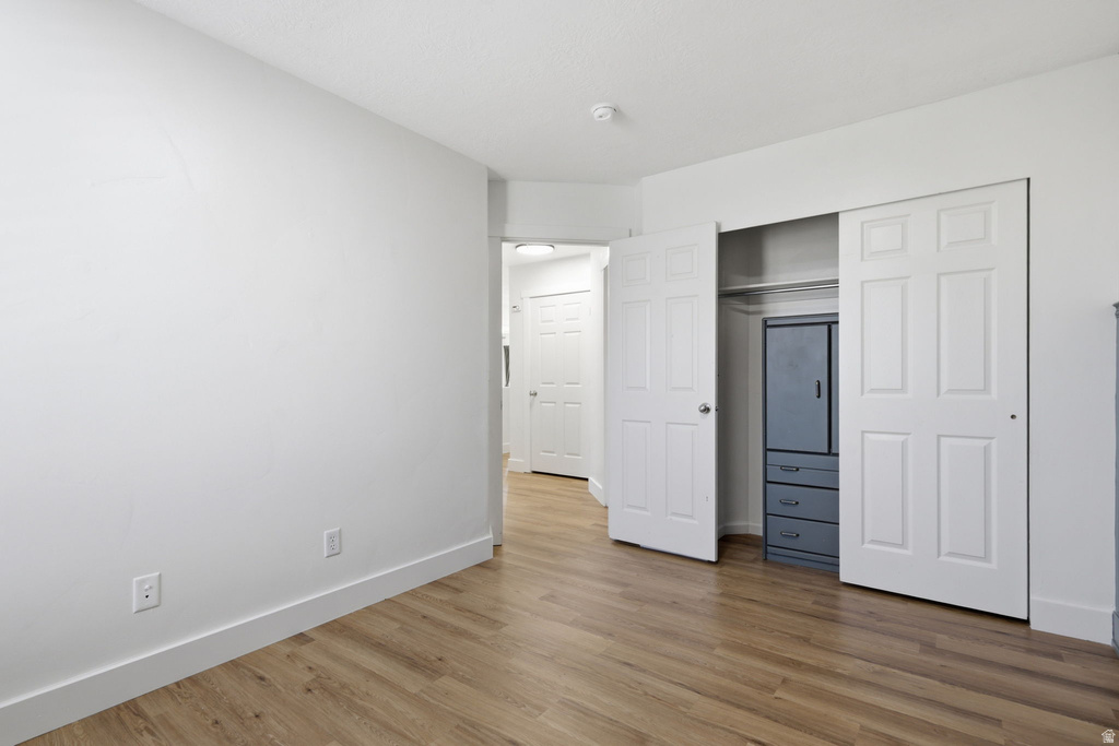 Spacious room featuring wood-finish flooring, white walls, and a recessed closet with bi-fold doors
