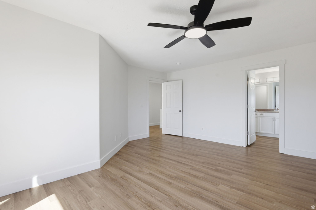 Spacious room featuring wood-finish flooring, white walls, and a contemporary ceiling fan