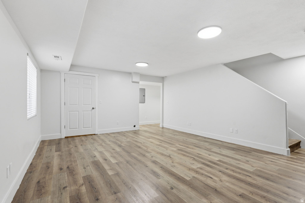 Spacious room featuring wood-finish flooring, recessed lighting, white trim, and a window with blinds
