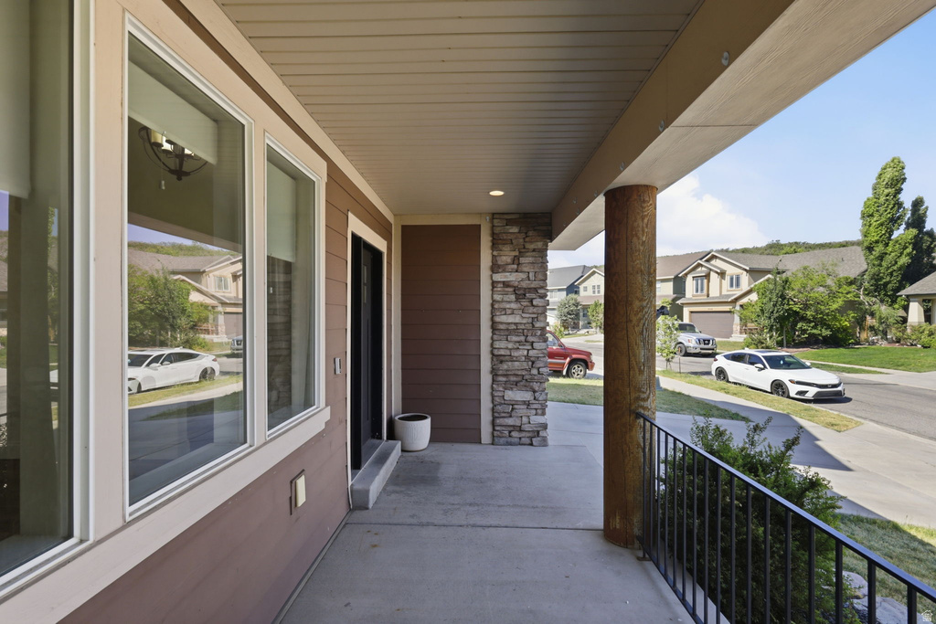 Covered porch featuring a wood-wrapped column, stacked stone accent, horizontal siding, black metal railing, and recessed ceiling lighting