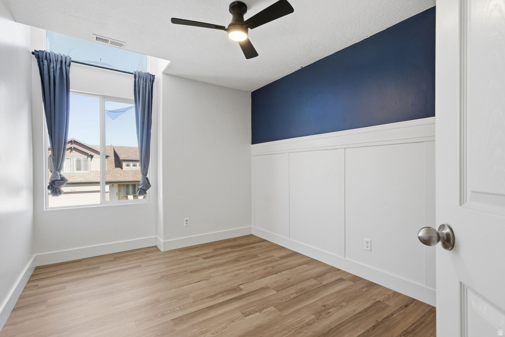Room featuring wood-finish flooring, a contemporary ceiling fan, and a window with a transom