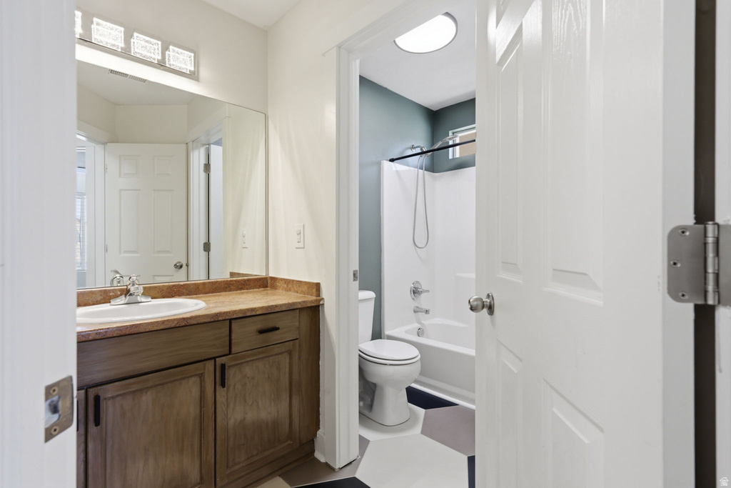 Bathroom featuring a wood-finish vanity with a built-in sink, a full-width mirror, and a three-light vanity fixture
