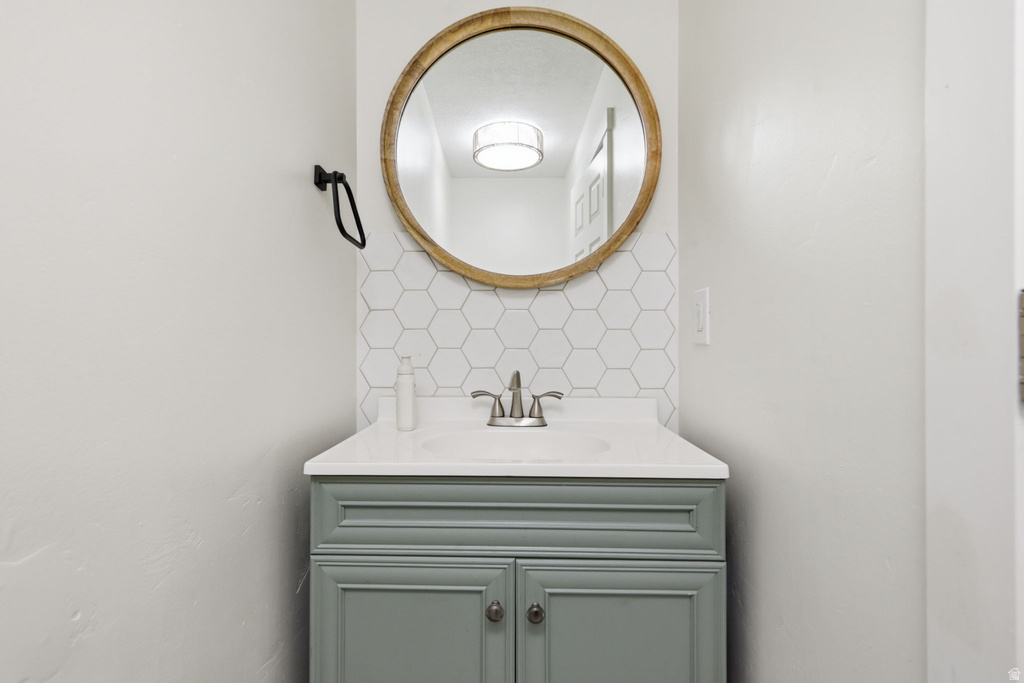 Bathroom vanity featuring a light green cabinet, white countertop, and brushed nickel faucet