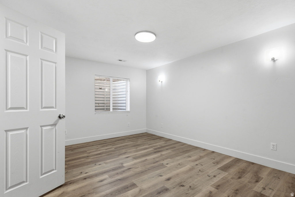 Room featuring wood-finish flooring, white walls, and a four-panel interior door