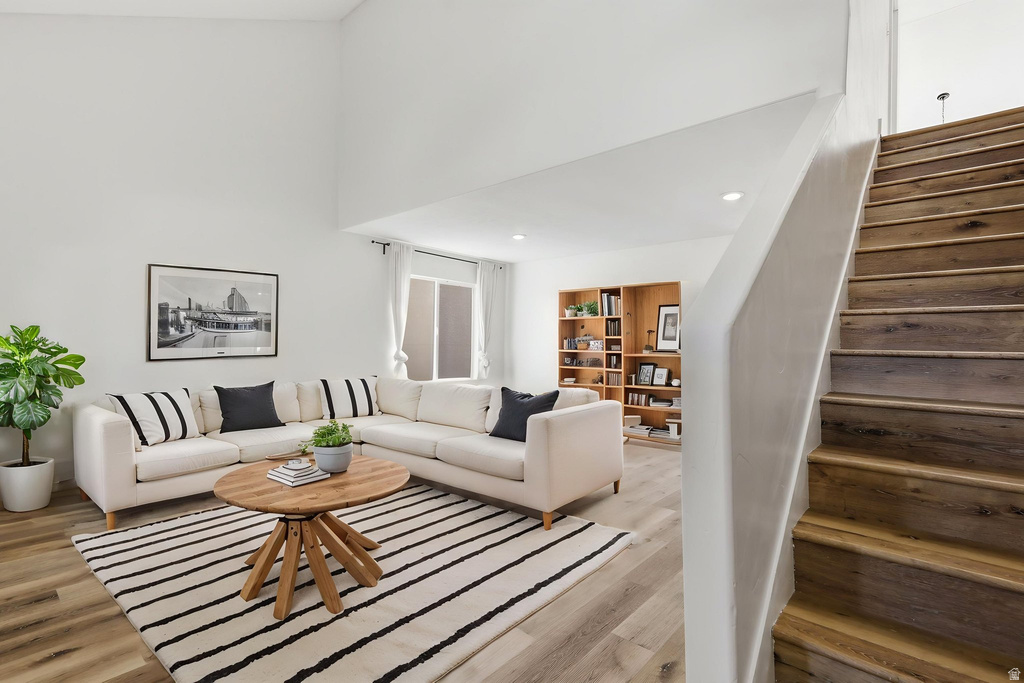 Vaulted ceiling living area featuring wood-finish flooring, recessed lighting, and a built-in bookshelf