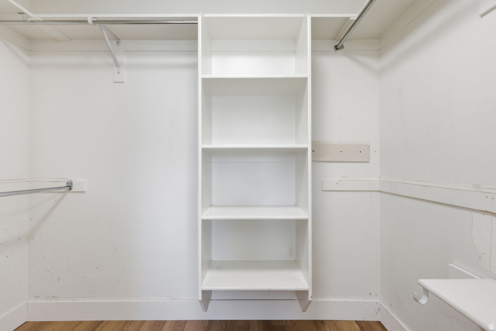 Custom closet system featuring built-in shelving, multiple hanging rods, and wood-finish flooring